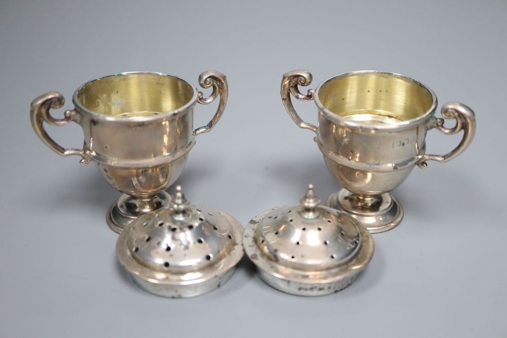A cased pair of late Victorian small silver trophy shaped pepper pots, Horace Woodward & Co, London, 1899, 67mm,